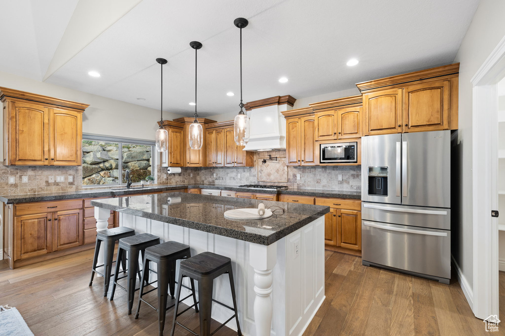 Kitchen featuring a kitchen island, backsplash, stainless steel appliances, and dark hardwood / wood-style floors