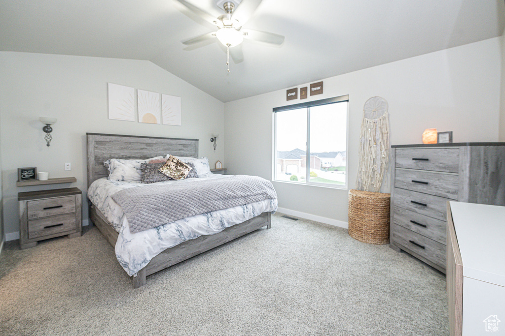 Bedroom featuring light colored carpet, lofted ceiling, and ceiling fan
