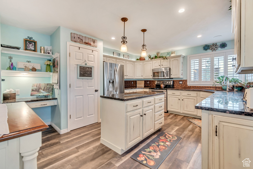 Kitchen featuring sink, decorative light fixtures, a kitchen island, stainless steel appliances, and hardwood / wood-style floors