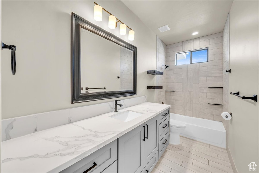 Full bathroom with tile flooring, tiled shower / bath, vanity, and toilet