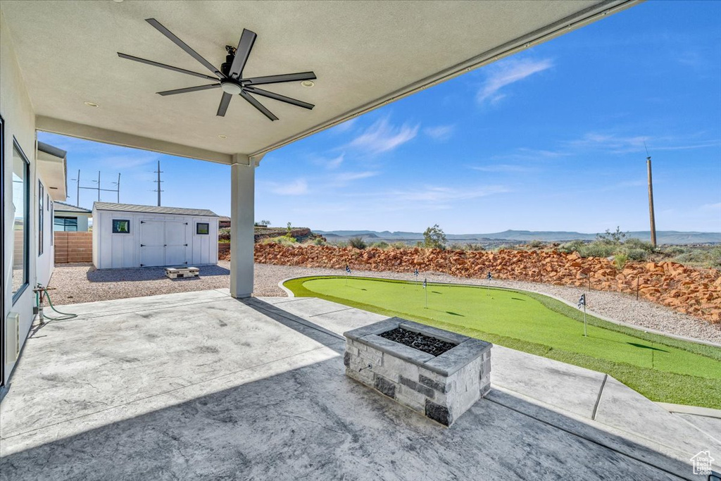 View of patio with a fire pit, ceiling fan, and a storage unit