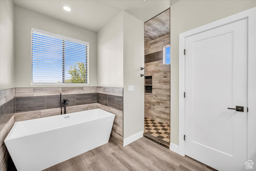 Bathroom featuring hardwood / wood-style floors, tile walls, and a bathtub