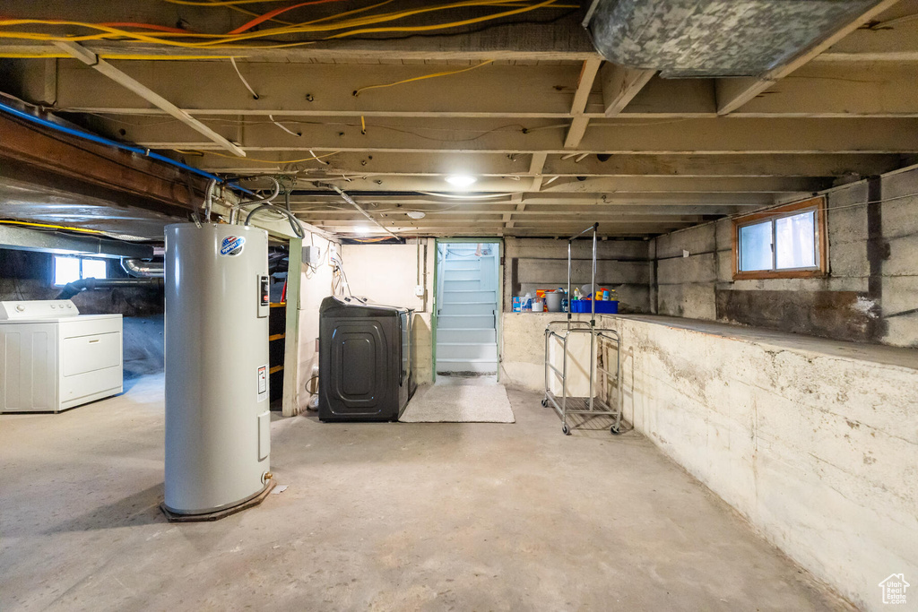 Basement featuring washing machine and clothes dryer and electric water heater