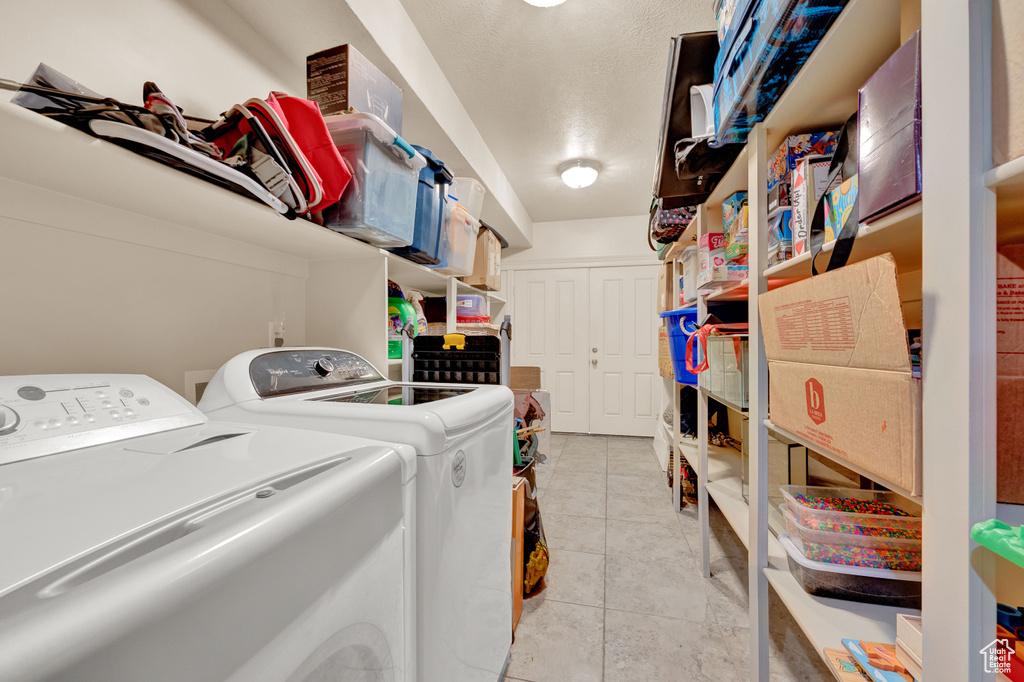 Clothes washing area featuring washer and clothes dryer and light tile floors