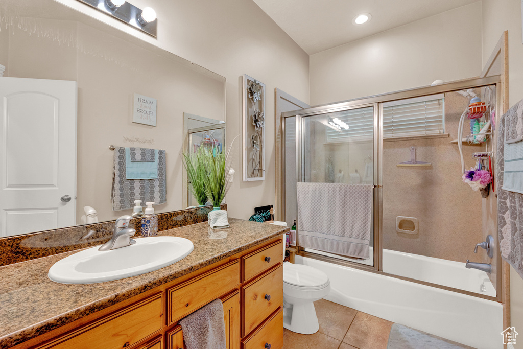 Full bathroom with tile flooring, vanity, toilet, and bath / shower combo with glass door