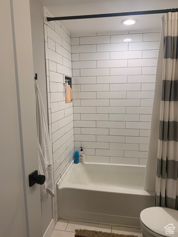 Bathroom featuring tile flooring, shower / bath combo, and toilet