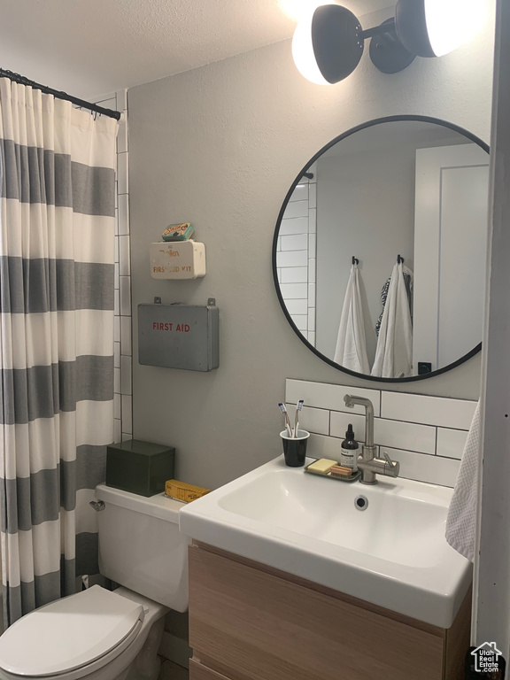 Bathroom featuring vanity, backsplash, and toilet