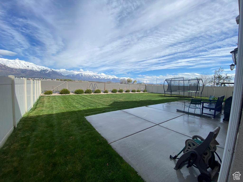 View of yard featuring a patio, a mountain view, and a trampoline