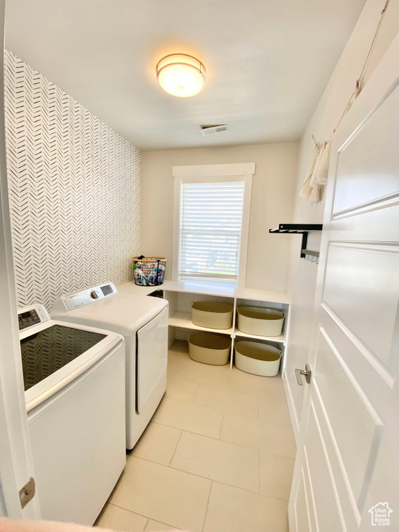 Washroom with light tile flooring and washer and dryer