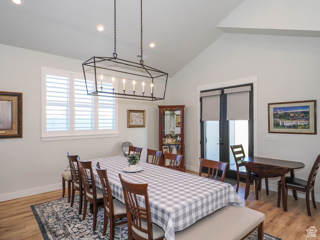 Dining area featuring vaulted ceiling, french doors, a notable chandelier, and light hardwood / wood-style floors