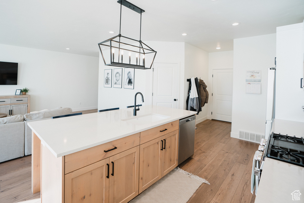 Kitchen featuring sink, light hardwood / wood-style floors, dishwasher, a center island with sink, and pendant lighting
