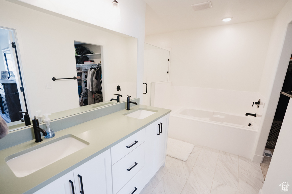Bathroom featuring double sink vanity, a tub, and tile floors