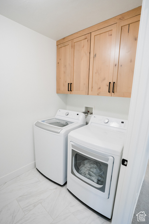 Clothes washing area featuring cabinets, hookup for a washing machine, light tile flooring, and washer and clothes dryer