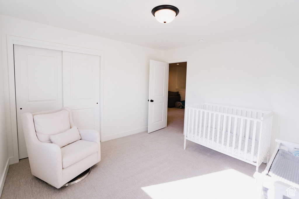 Bedroom with light colored carpet, a closet, and a nursery area