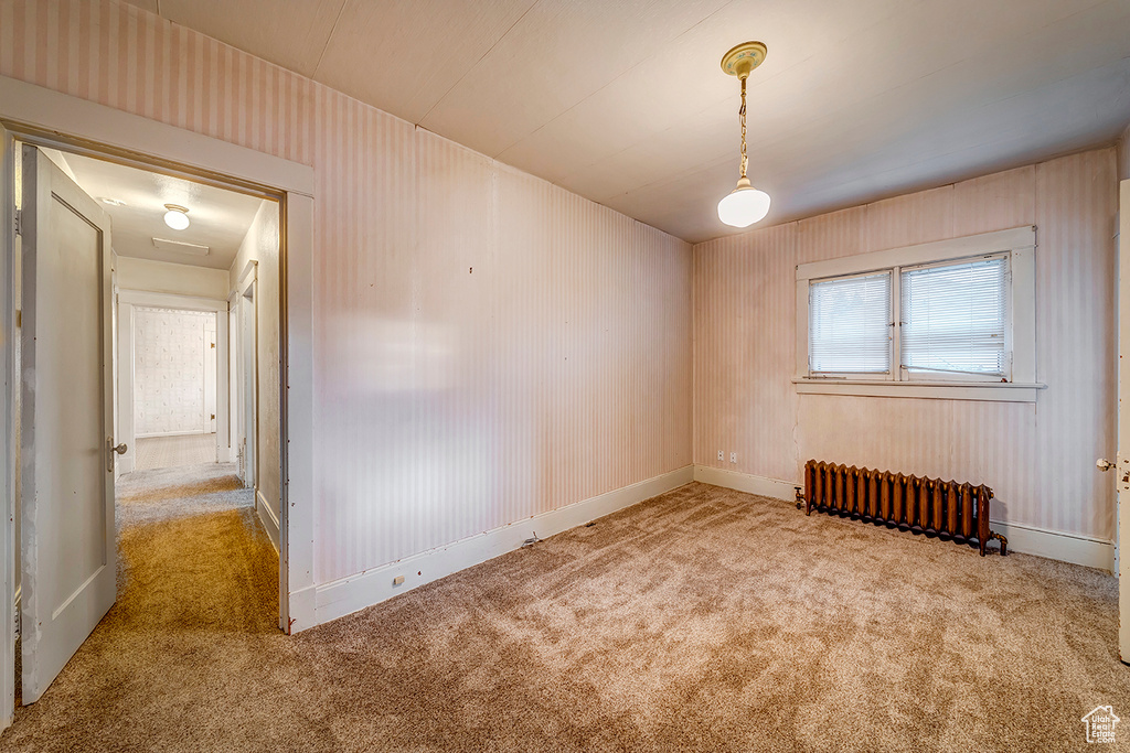 Carpeted empty room featuring radiator heating unit