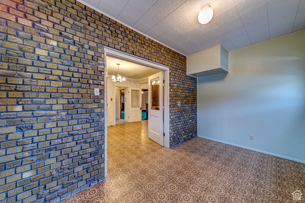 Tiled empty room with brick wall and an inviting chandelier