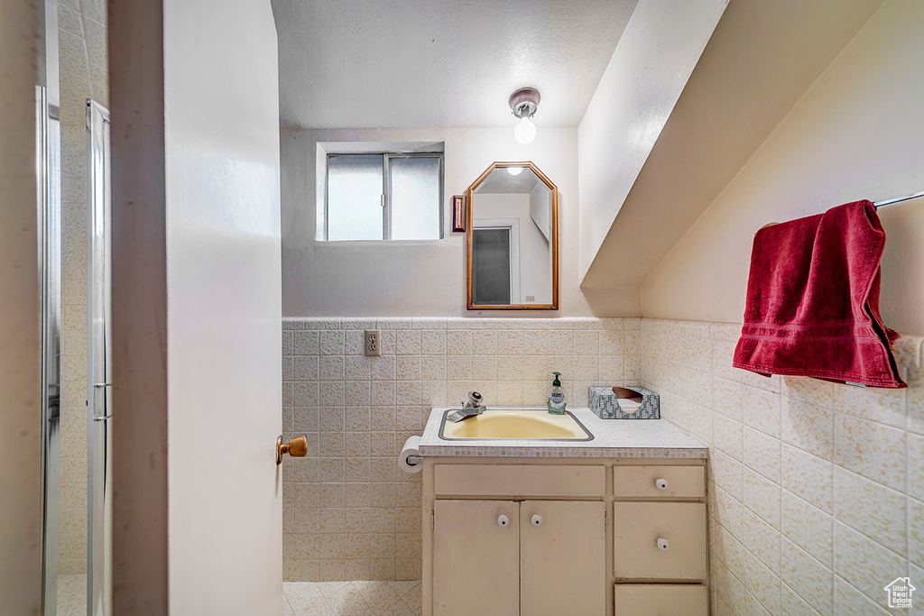 Bathroom featuring vanity, tasteful backsplash, and tile walls
