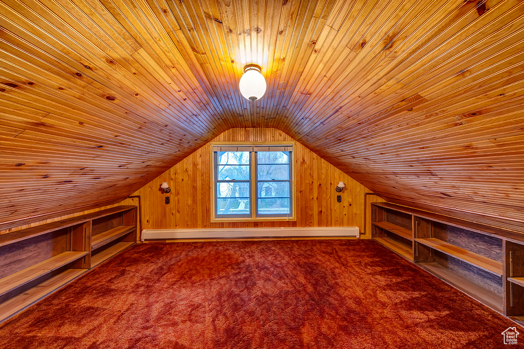 Additional living space with wood walls, a baseboard radiator, wooden ceiling, and vaulted ceiling