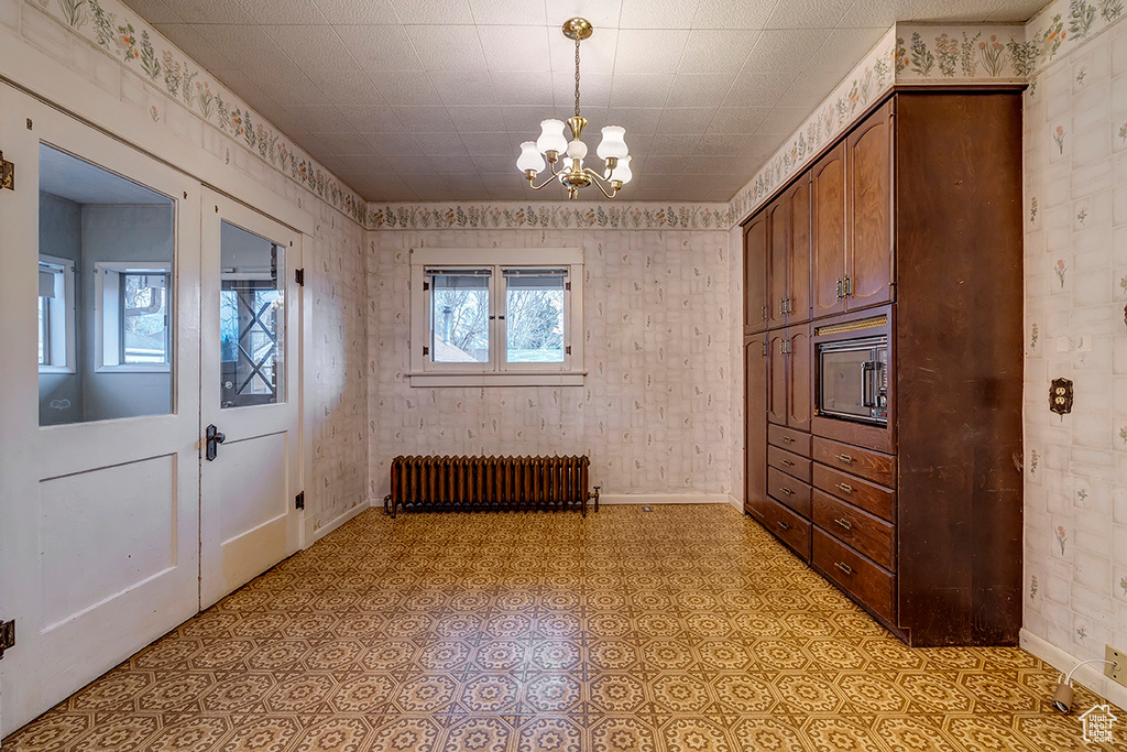 Interior space featuring an inviting chandelier, radiator, and light tile flooring