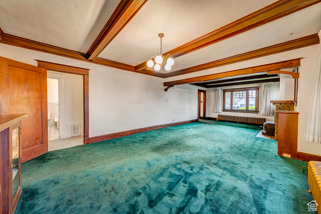 Carpeted spare room featuring beam ceiling, radiator heating unit, and an inviting chandelier