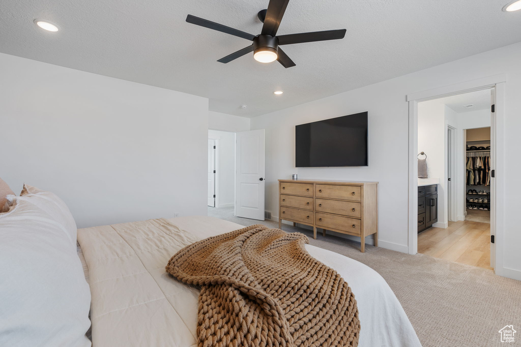 Bedroom featuring light colored carpet, ensuite bath, and ceiling fan