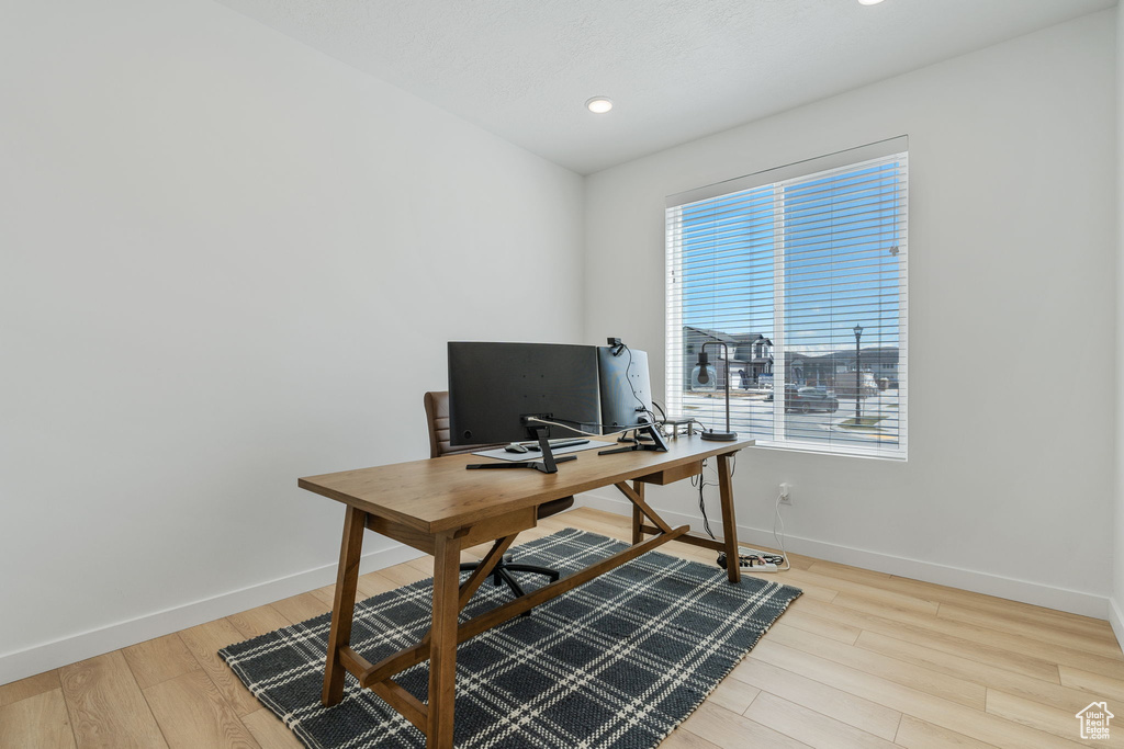 Office with a wealth of natural light and light hardwood / wood-style flooring