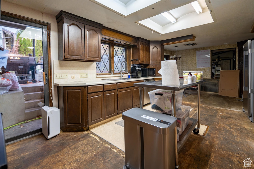 Kitchen featuring sink, dark brown cabinetry, stainless steel dishwasher, and backsplash