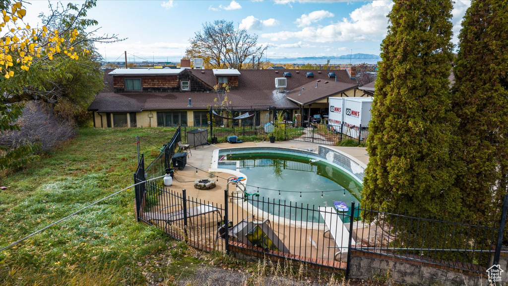 View of swimming pool with a patio, a lawn, and a hot tub