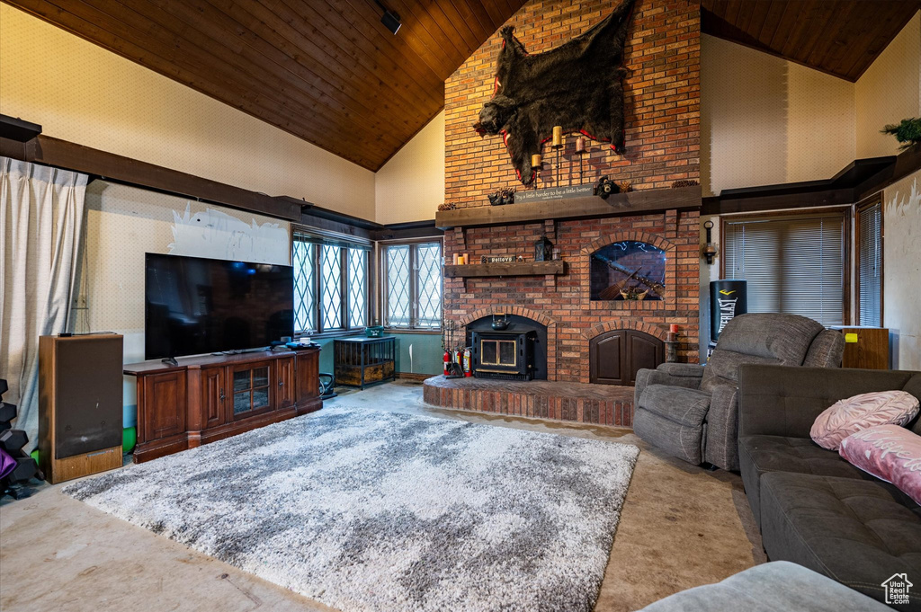 Living room featuring a wood stove, high vaulted ceiling, wood ceiling, a fireplace, and brick wall