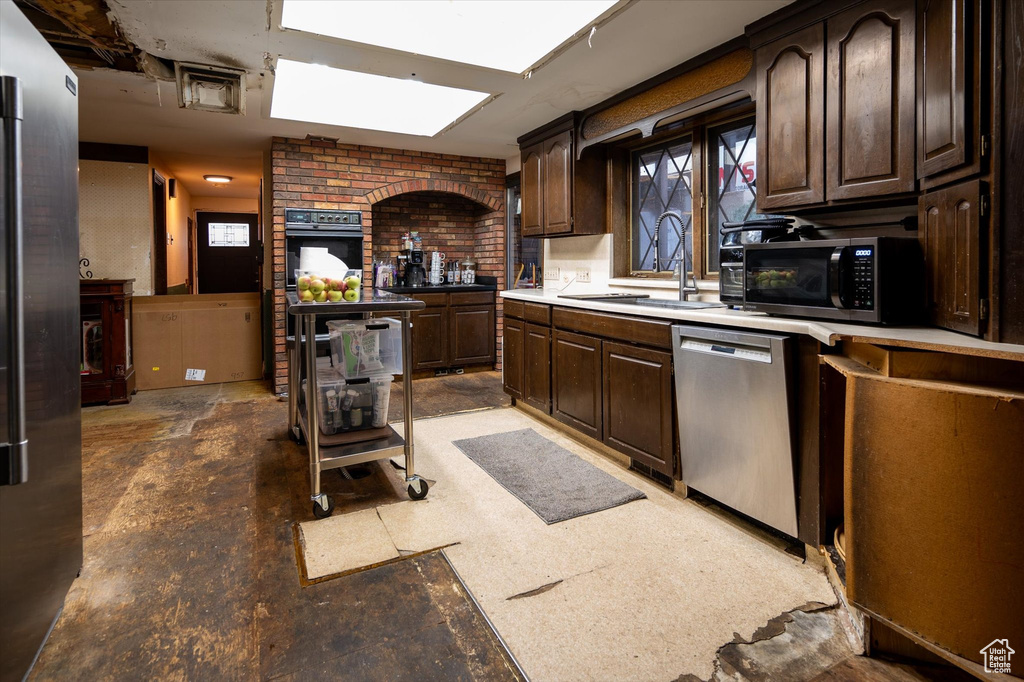 Kitchen with appliances with stainless steel finishes, sink, and dark brown cabinets