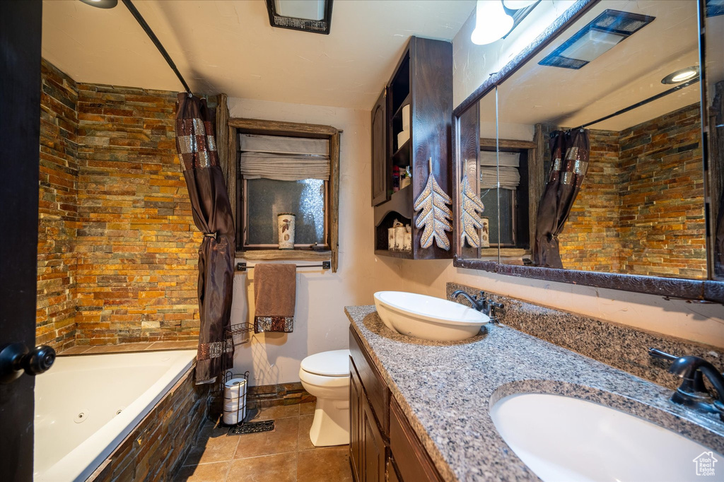 Full bathroom featuring shower / bath combo, double sink, tile flooring, vanity with extensive cabinet space, and toilet