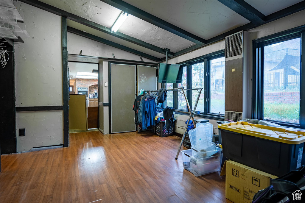 Misc room with lofted ceiling with beams, a healthy amount of sunlight, and hardwood / wood-style flooring