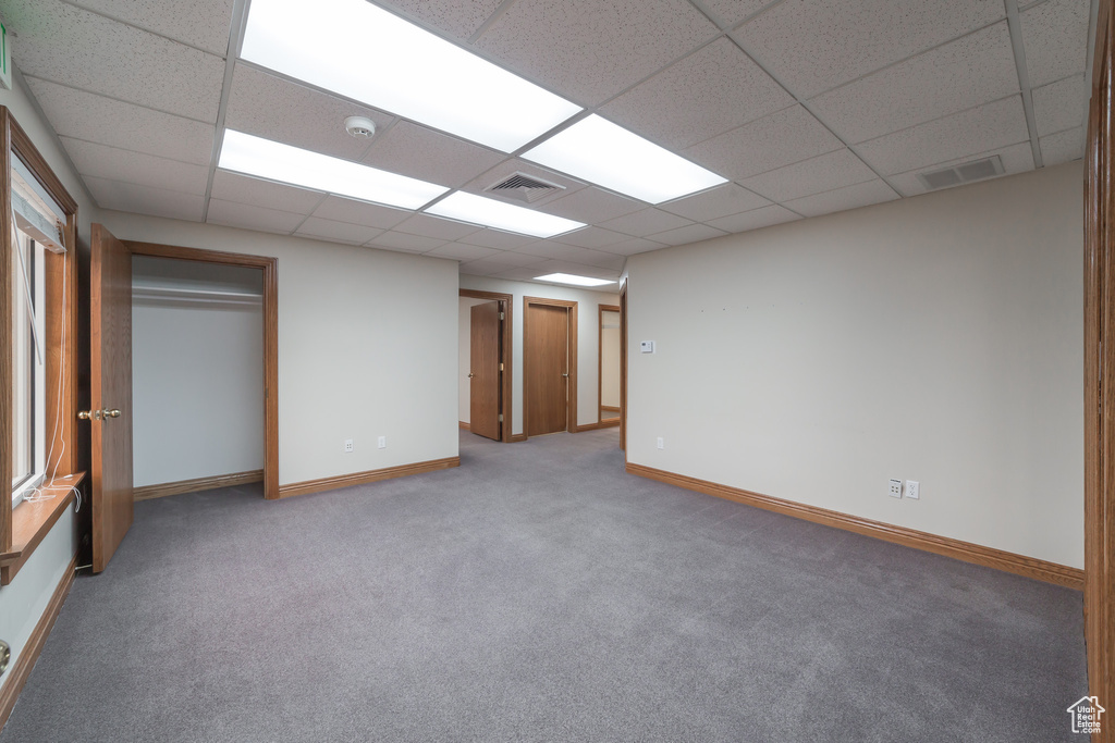 Unfurnished bedroom featuring light colored carpet, a paneled ceiling, and a closet