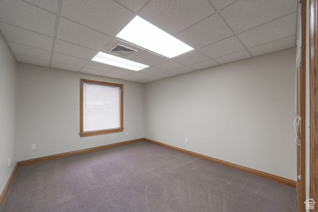 Empty room with carpet and a paneled ceiling