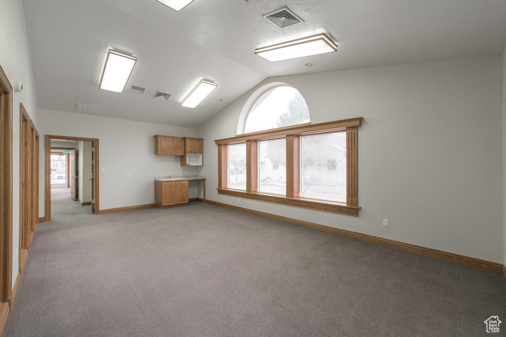 Unfurnished living room featuring light colored carpet and lofted ceiling
