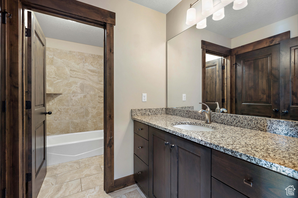 Bathroom with a textured ceiling, vanity, and tile flooring