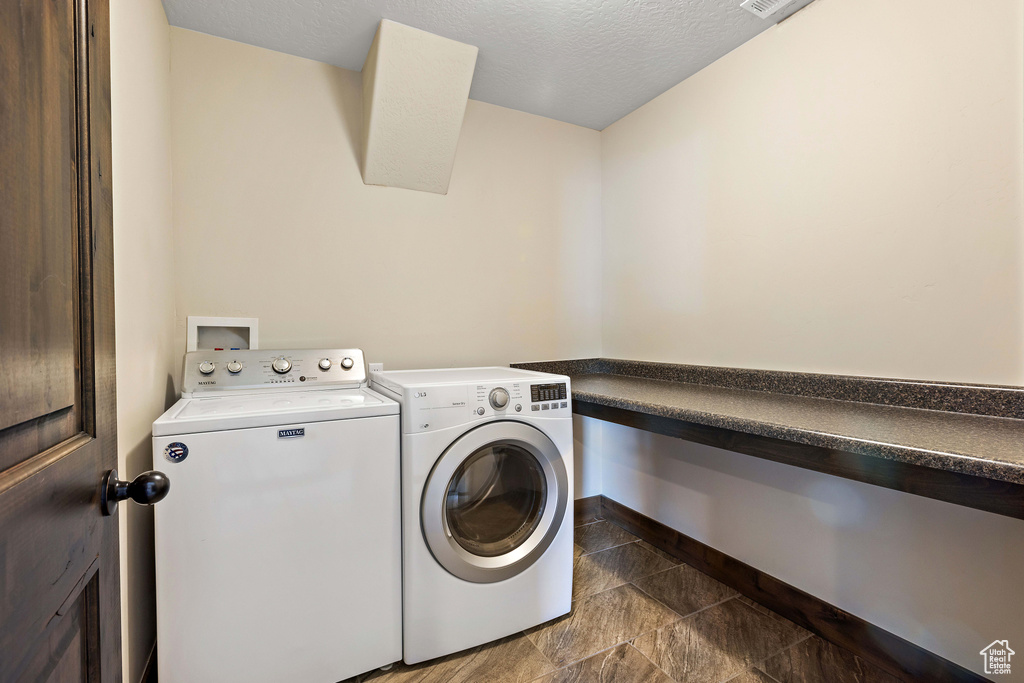 Laundry area featuring a textured ceiling, dark tile flooring, washing machine and dryer, and washer hookup