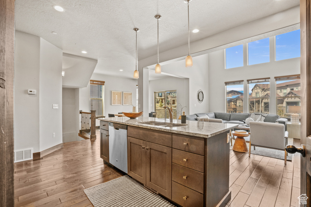 Kitchen with a wealth of natural light, light hardwood / wood-style floors, hanging light fixtures, and stainless steel dishwasher