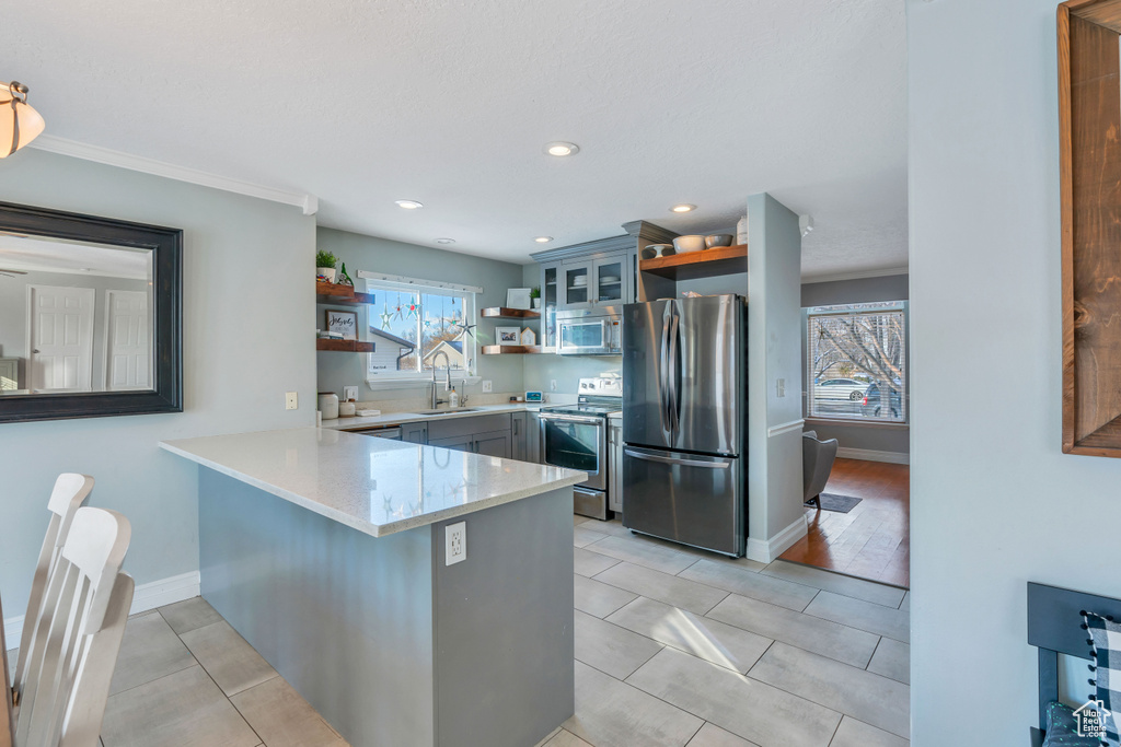 Kitchen with sink, stainless steel appliances, kitchen peninsula, and light tile floors