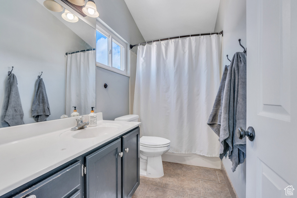Full bathroom with shower / tub combo, lofted ceiling, toilet, tile floors, and vanity