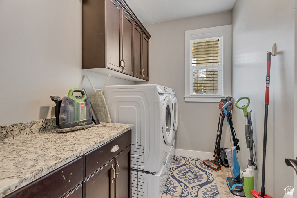 Clothes washing area featuring independent washer and dryer, cabinets, and light tile flooring
