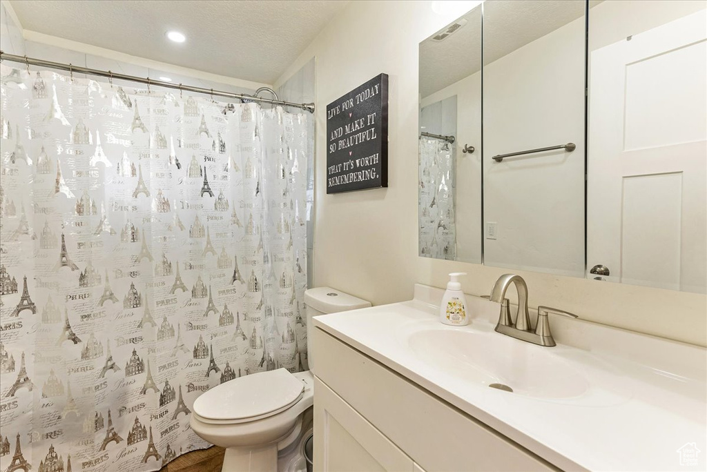 Bathroom featuring vanity, toilet, and a textured ceiling