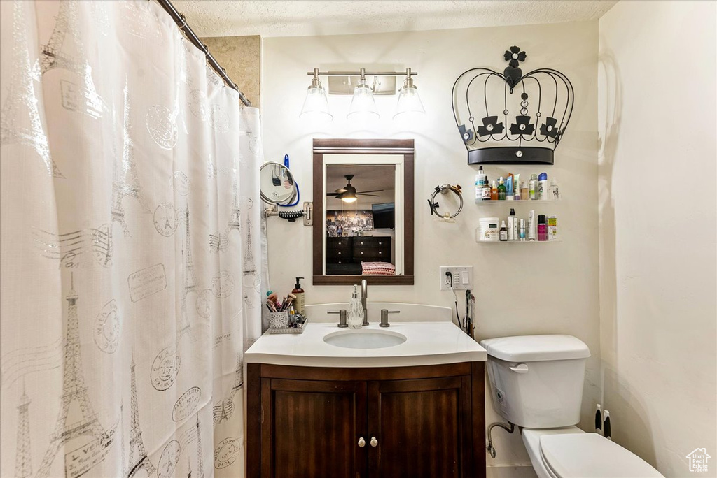 Bathroom with ceiling fan, vanity, toilet, and a textured ceiling
