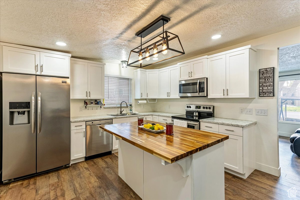 Kitchen with white cabinets, a center island, stainless steel appliances, and dark wood-type flooring
