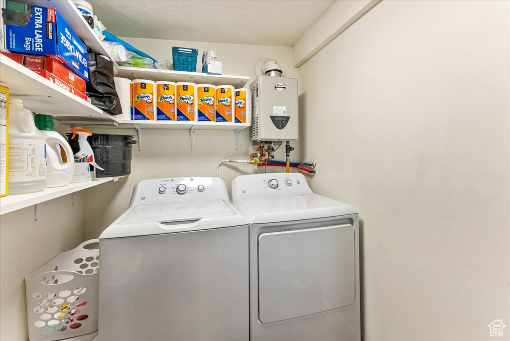 Laundry area featuring water heater, washing machine and dryer, and a textured ceiling