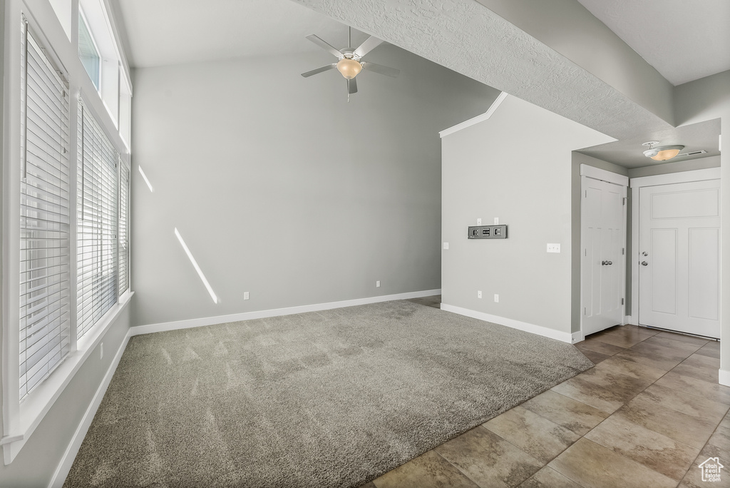 Tiled empty room featuring ceiling fan and lofted ceiling
