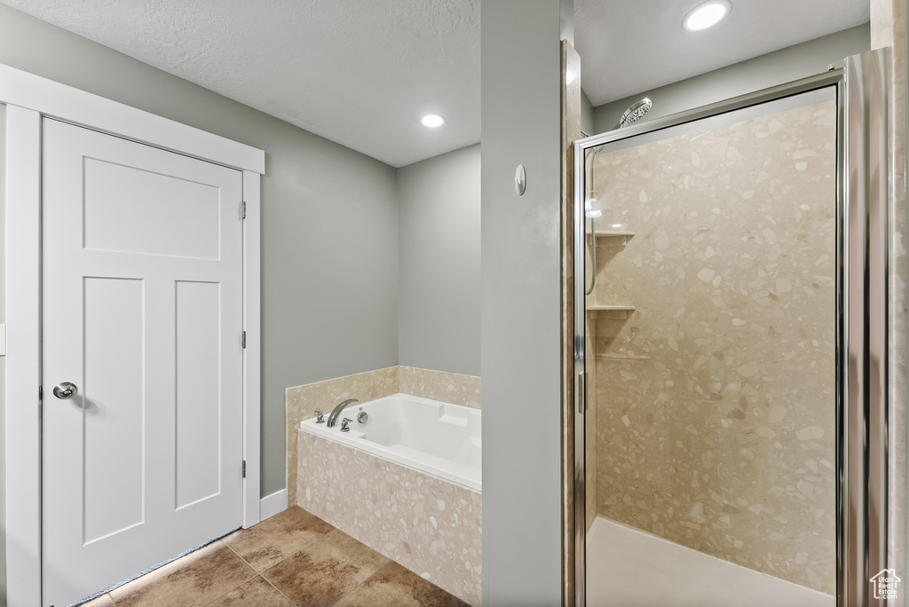 Bathroom with tile floors, a textured ceiling, and plus walk in shower