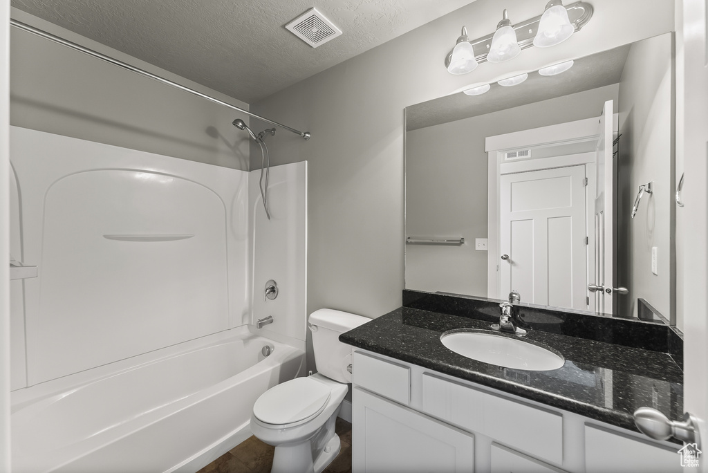 Full bathroom featuring toilet, vanity, a textured ceiling, and  shower combination