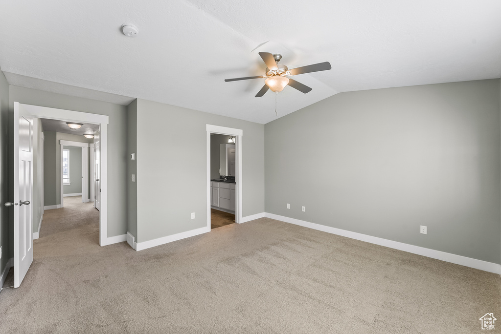 Unfurnished bedroom with ceiling fan, vaulted ceiling, light carpet, and ensuite bathroom