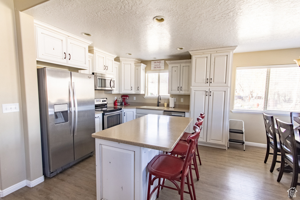 Kitchen with a center island, hardwood / wood-style flooring, stainless steel appliances, and a breakfast bar area